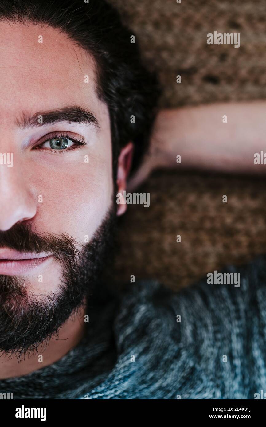 Primo piano di bell'uomo con le mani dietro la testa sdraiata pavimento a casa Foto Stock
