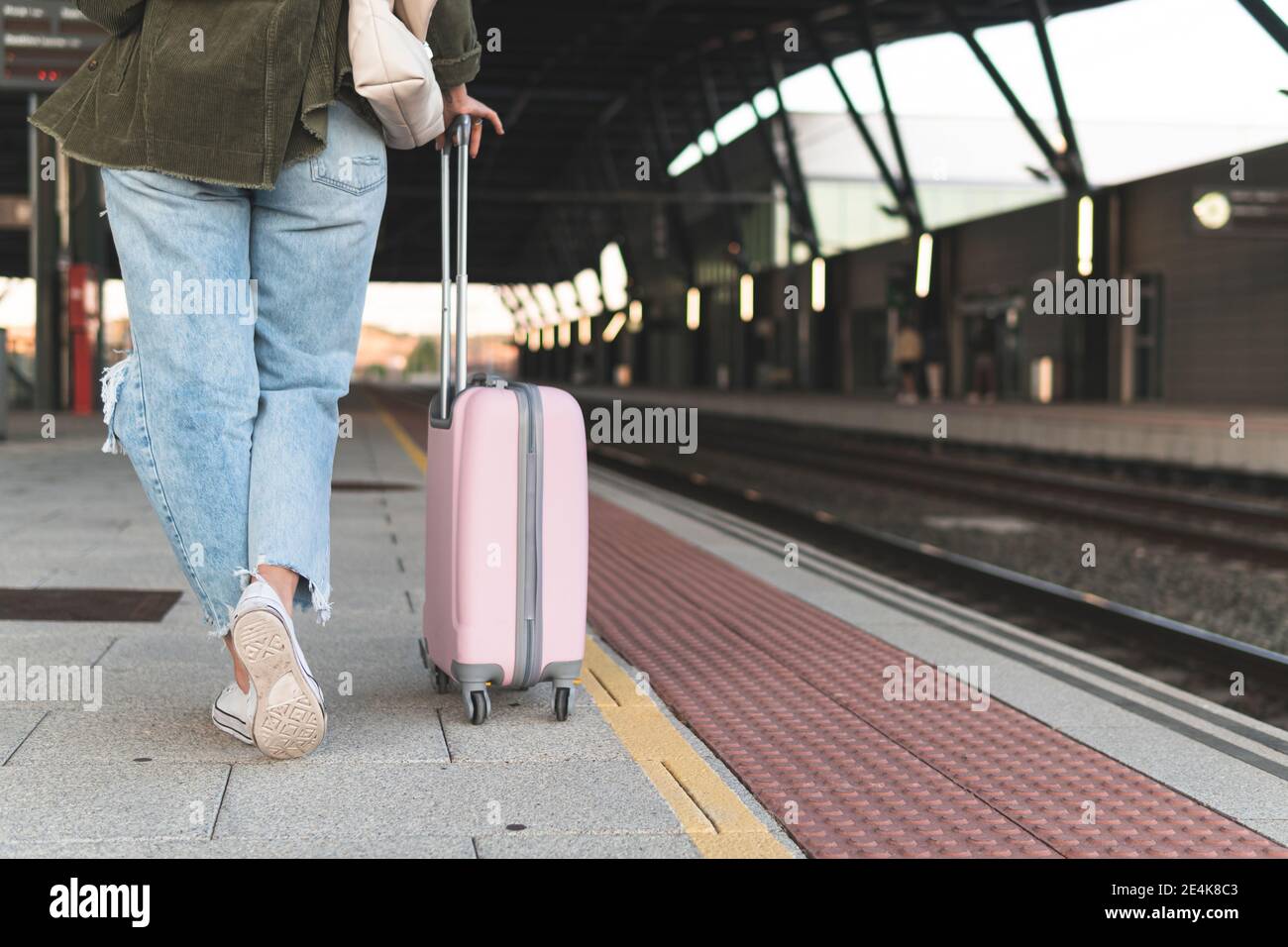Gambe di giovane donna con valigia che cammina sulla stazione ferroviaria piattaforma Foto Stock