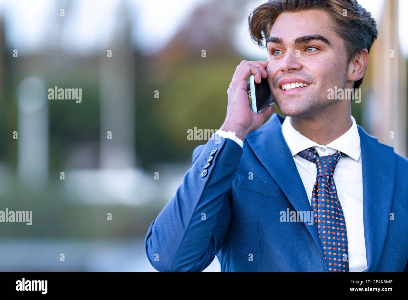 Sorridente giovane uomo d'affari che comunica sul telefono cellulare Foto Stock