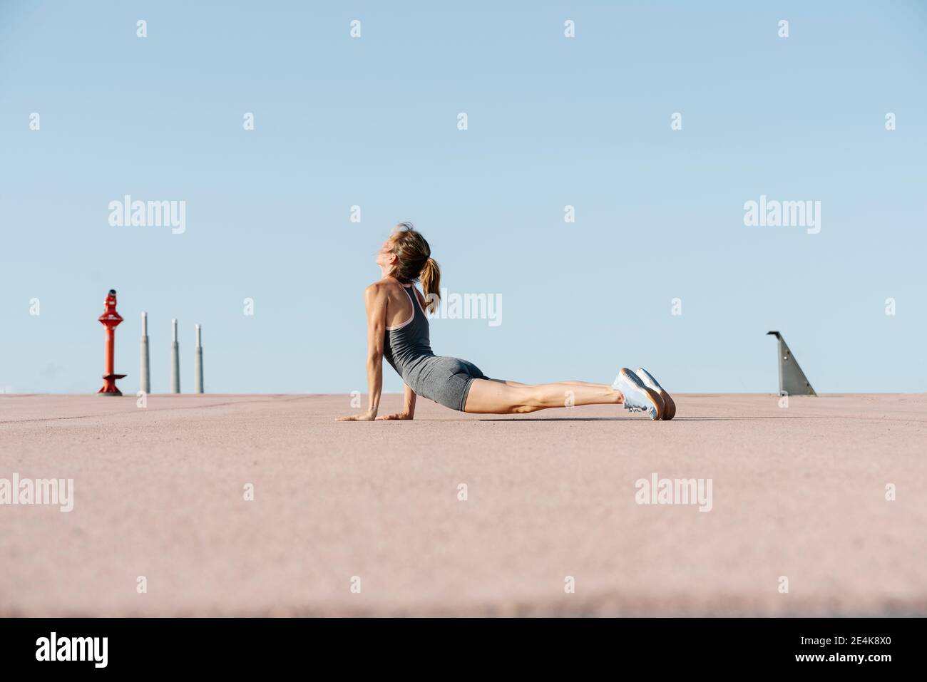 Yoga femminile sportivo spermssonparticing contro il cielo limpido Foto Stock
