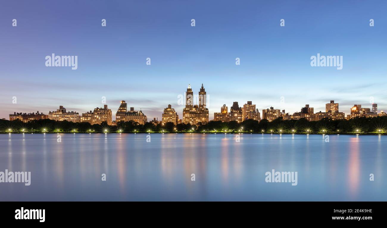 USA, New York, New York City, skyline di Manhattan illuminato al crepuscolo visto attraverso il bacino idrico Jacqueline Kennedy Onassis Foto Stock