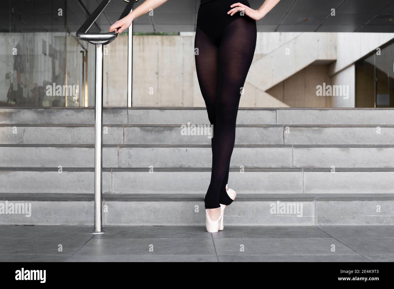 Gambe di ballerina su punte a ringhiera in cemento moderno edificio Foto Stock