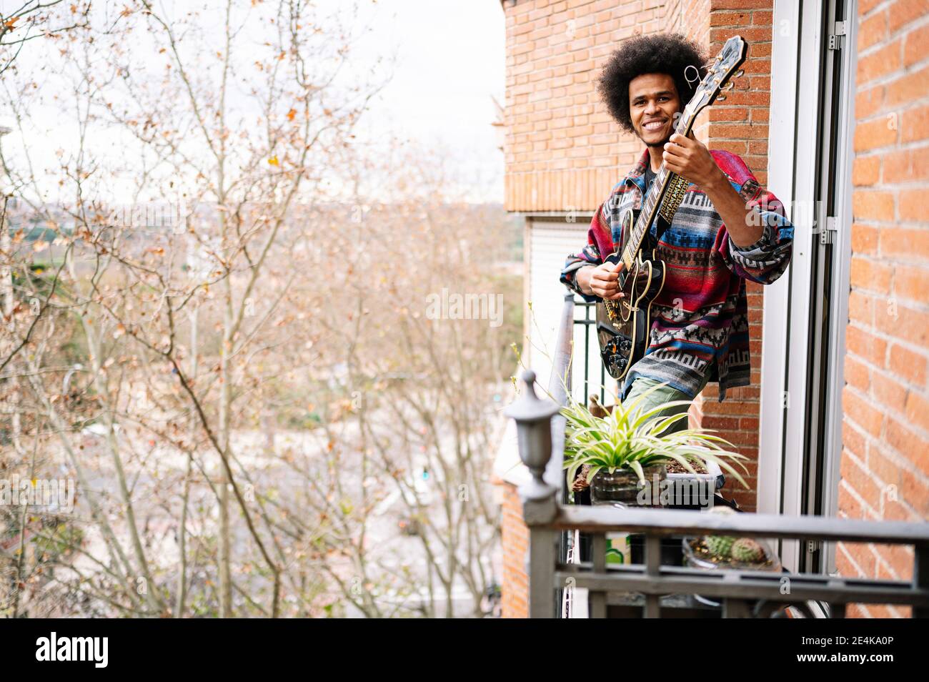 Afro musicista maschile praticando sassofono in balcone a casa Foto Stock