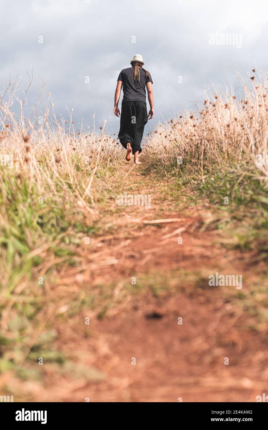 Giovane uomo che cammina nel campo verso il cielo nuvoloso a Santander, Spagna Foto Stock