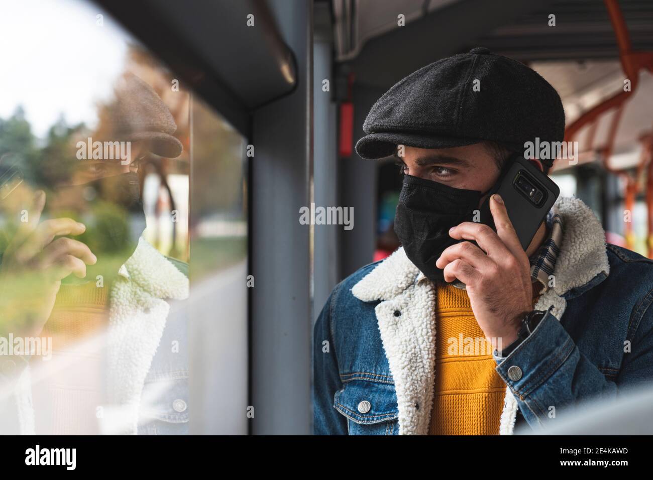 Il pendolari indossa una maschera protettiva per il viso durante la chiamata telefonica in autobus Foto Stock
