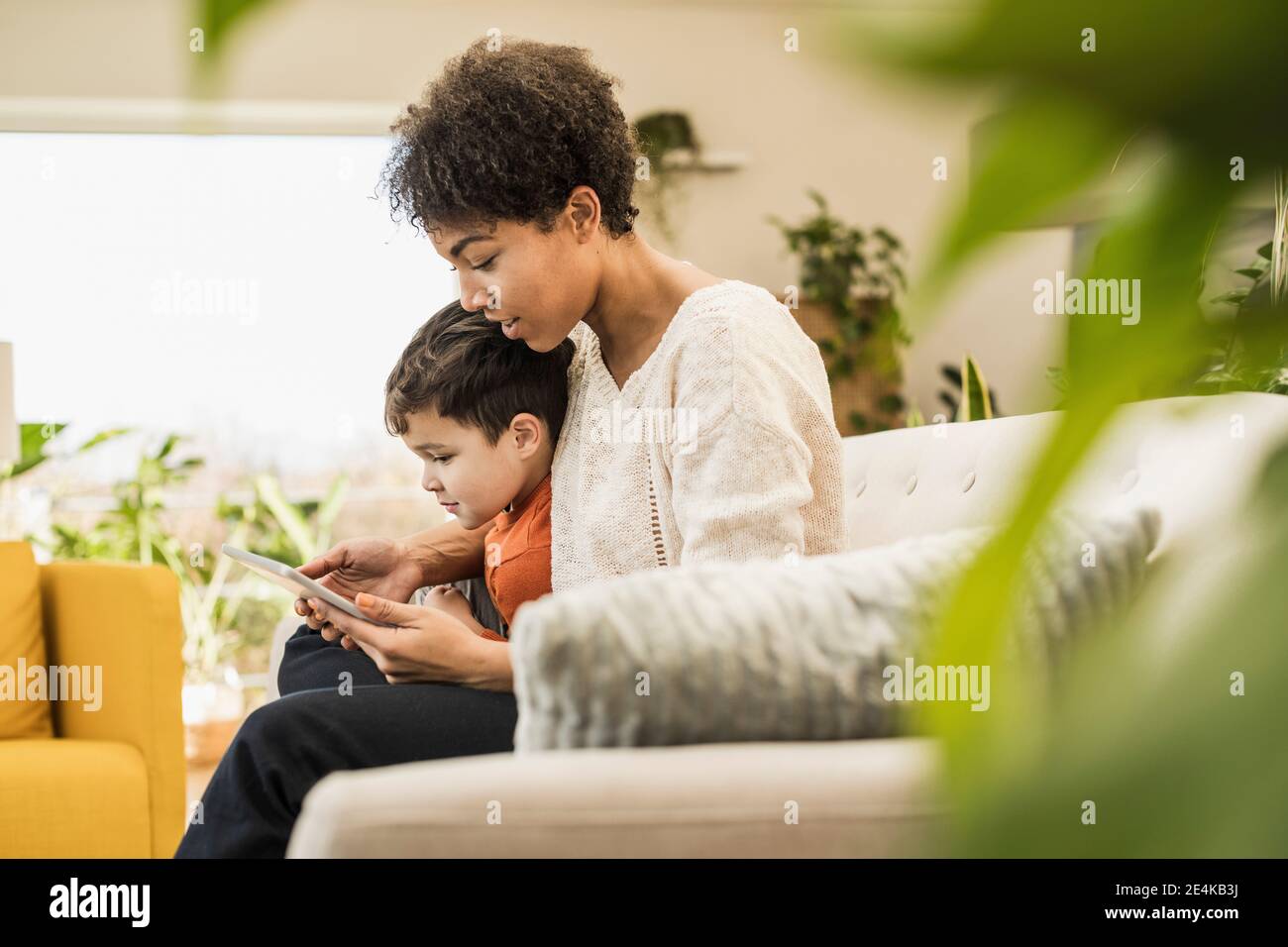 Madre e figlio utilizzano un tablet digitale mentre si è seduti a casa Foto Stock