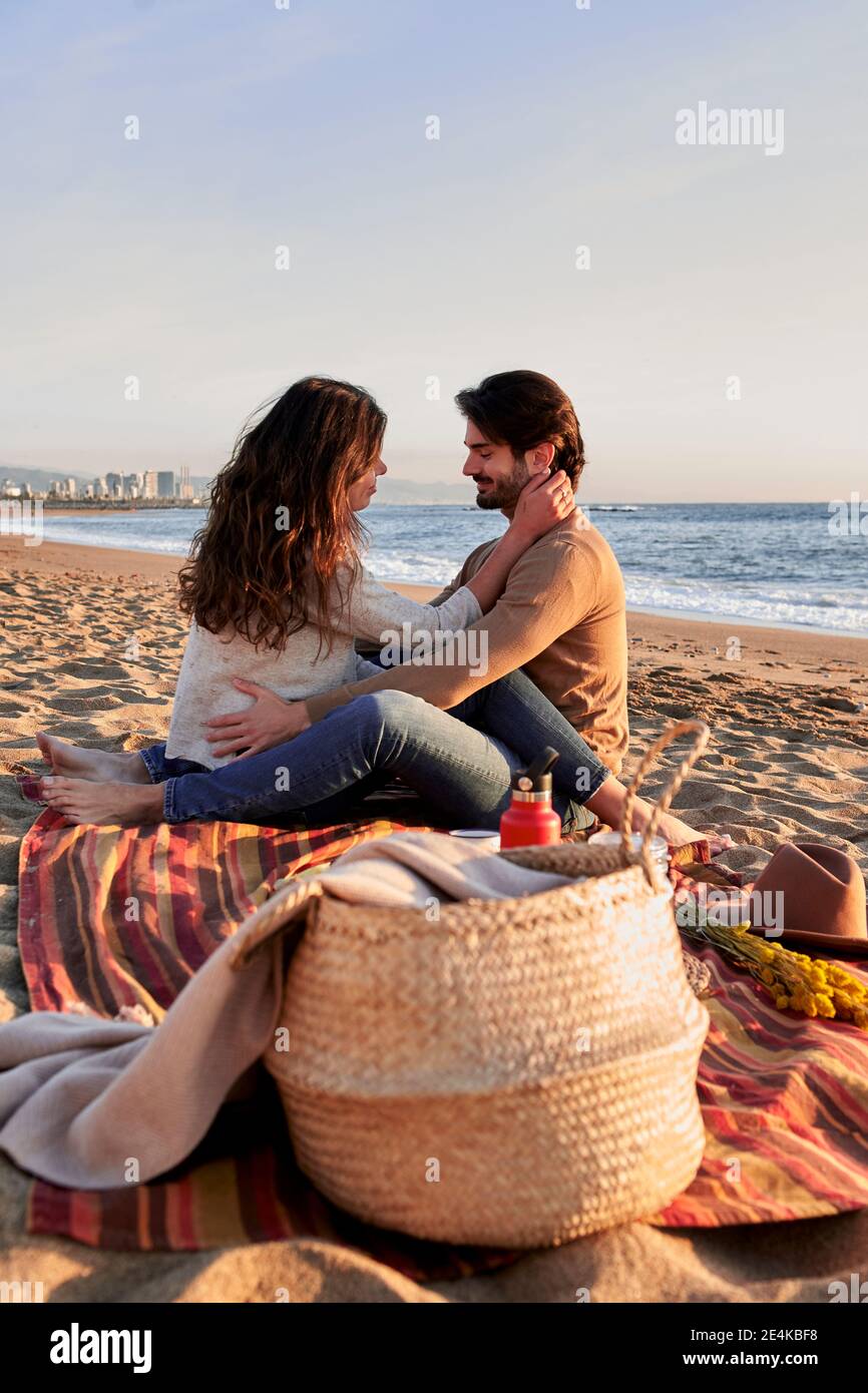 Coppia che fa romanticismo mentre si siede sulla spiaggia Foto Stock