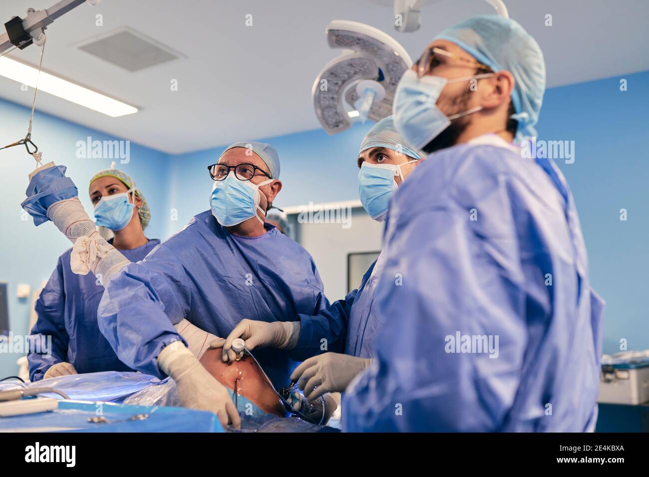 I professionisti lavorano in team con chirurgia artroscopica della spalla mentre sono in funzione camera durante COVID-19 Foto Stock
