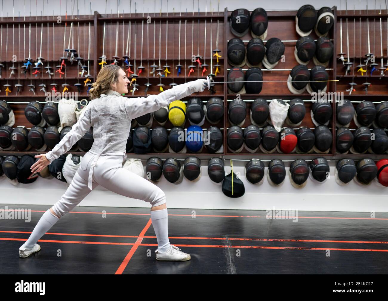 Donna in scherma vestito che pratica in palestra Foto Stock