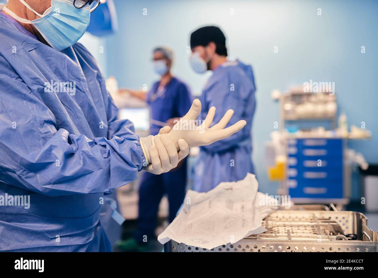 Medico maturo che indossa guanti protettivi mentre si è in piedi nella sala operatoria Foto Stock