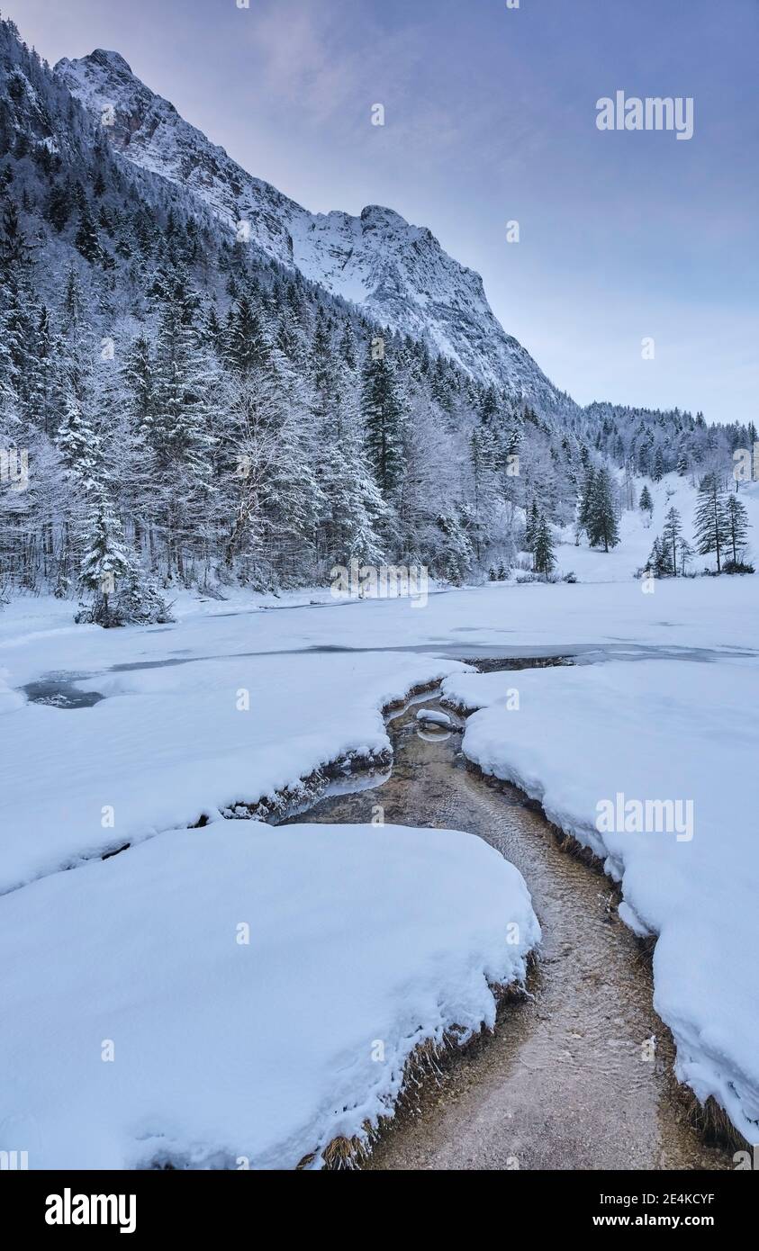 Ruscello che scorre attraverso terra coperta di neve Foto Stock