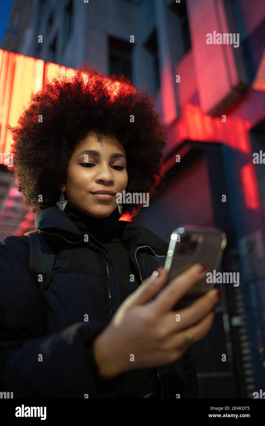 Giovane donna con acconciatura afro in città Foto Stock
