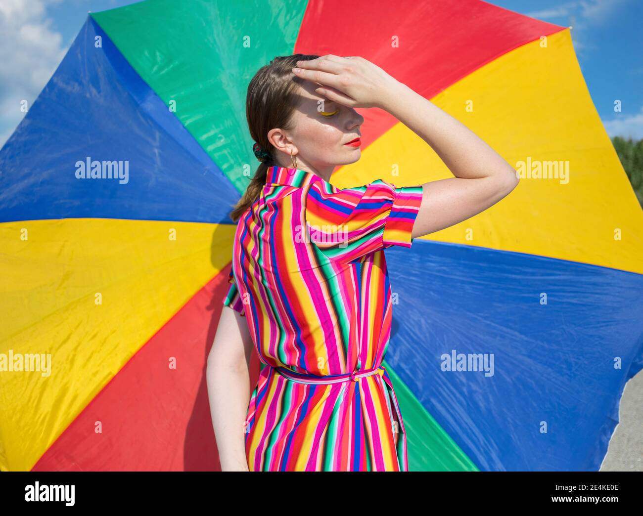 Donna mid adulta con ombrellone colorato in giornata di sole Foto Stock