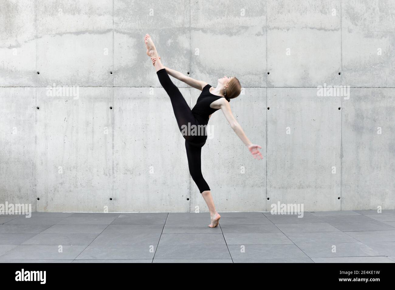 Ballerina in nero leotard danzante di fronte al muro di cemento Foto Stock