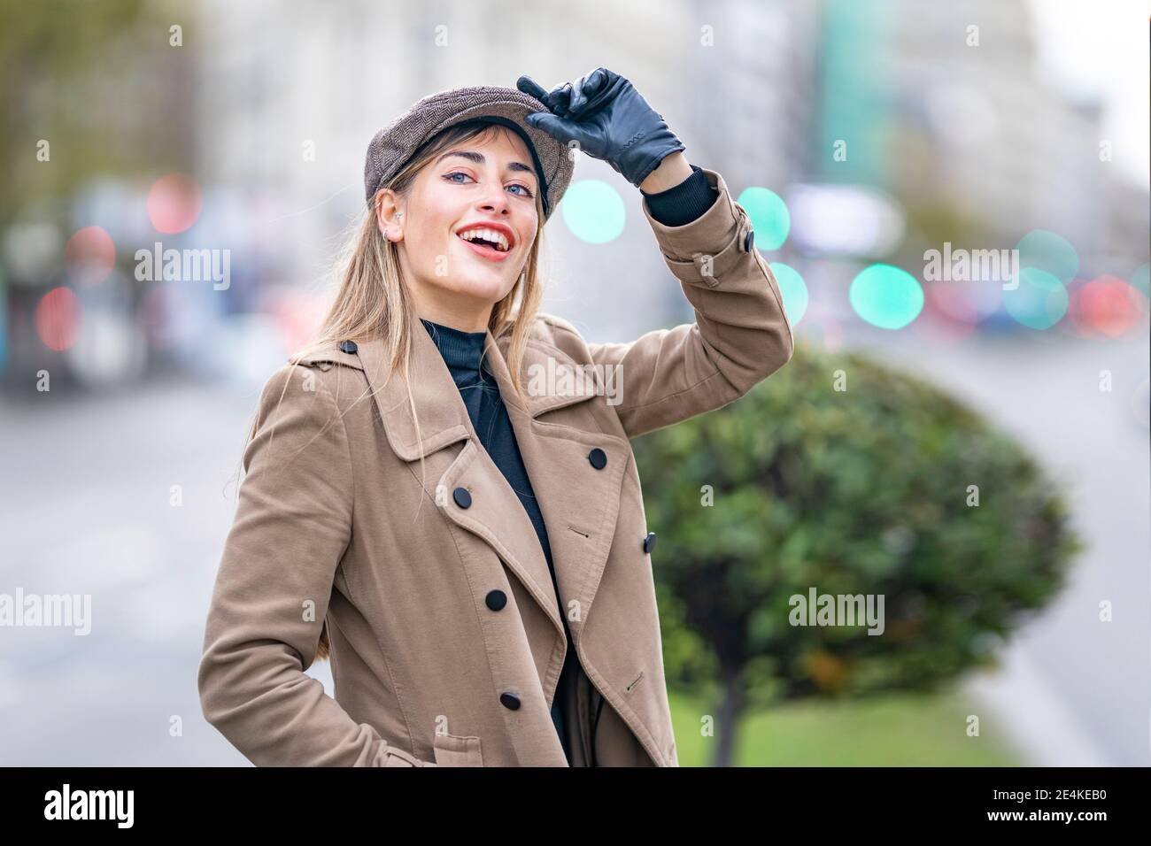 Donna attraente che tiene il cappuccio mentre osserva via Foto Stock