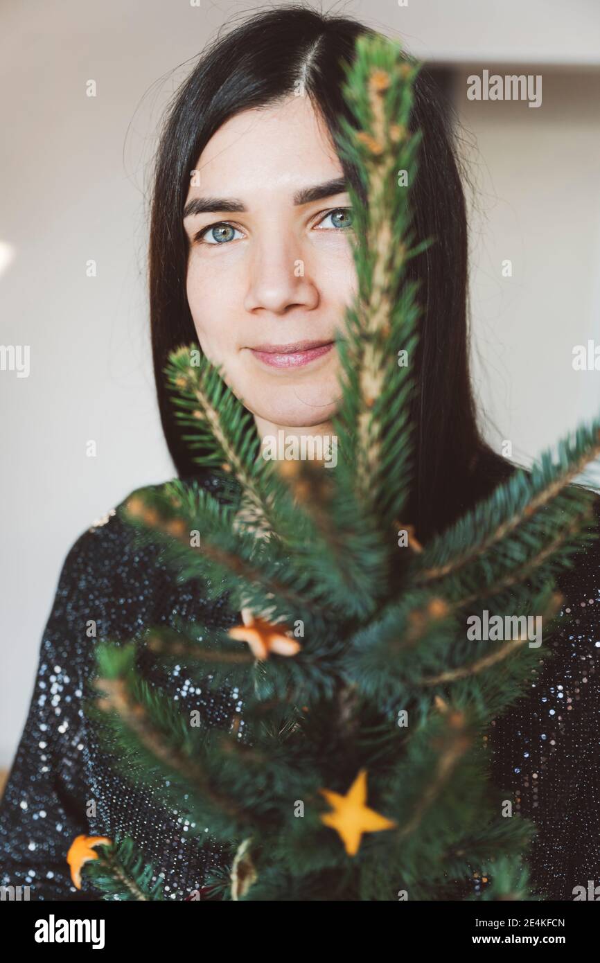 Donna adulto medio che tiene il piccolo albero di Natale mentre sta a. casa Foto Stock