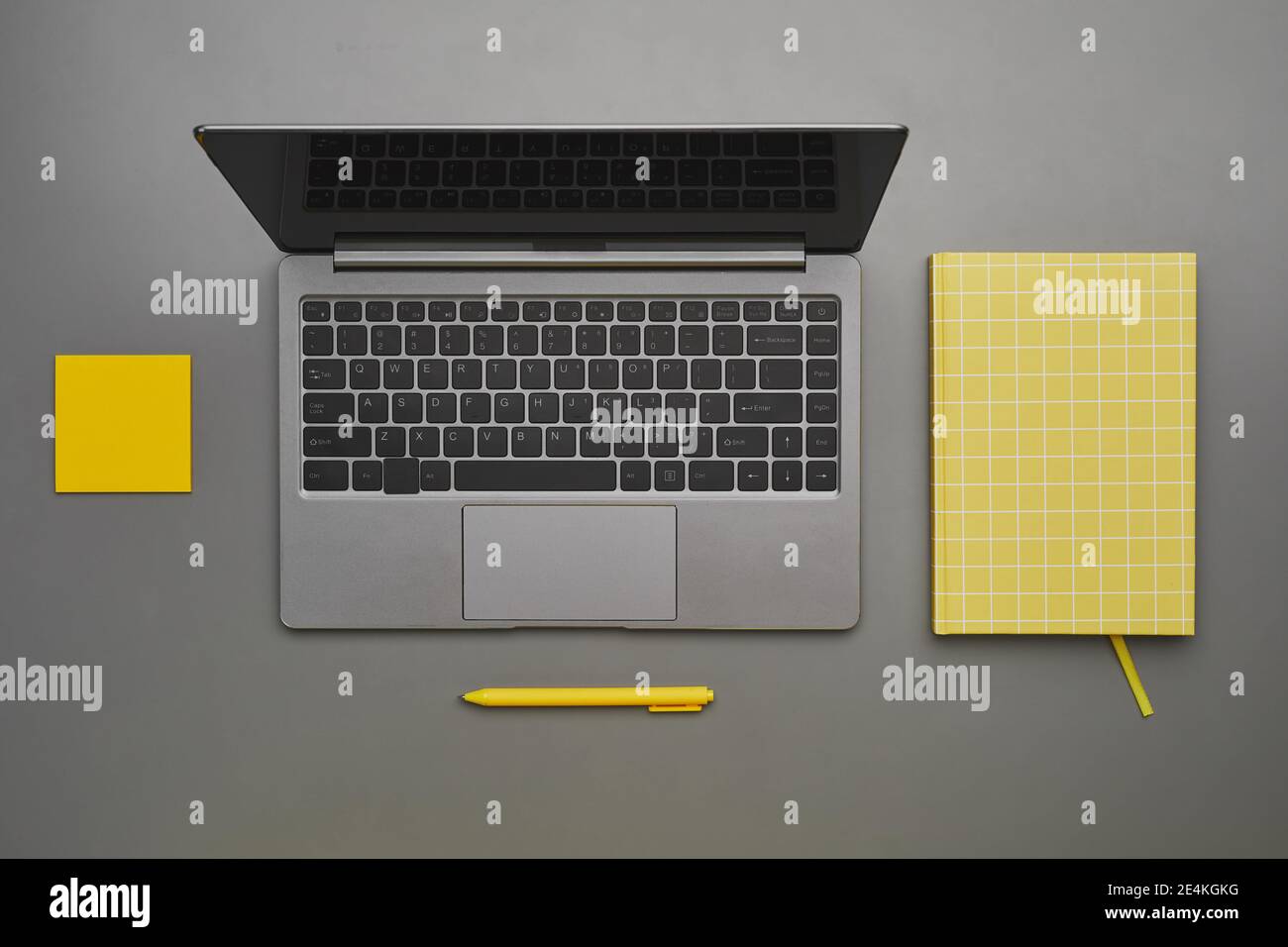 Sfondo grigio e giallo grafico del notebook con accessori aziendali alla scrivania, vista dall'alto in piano, spazio per la copia Foto Stock