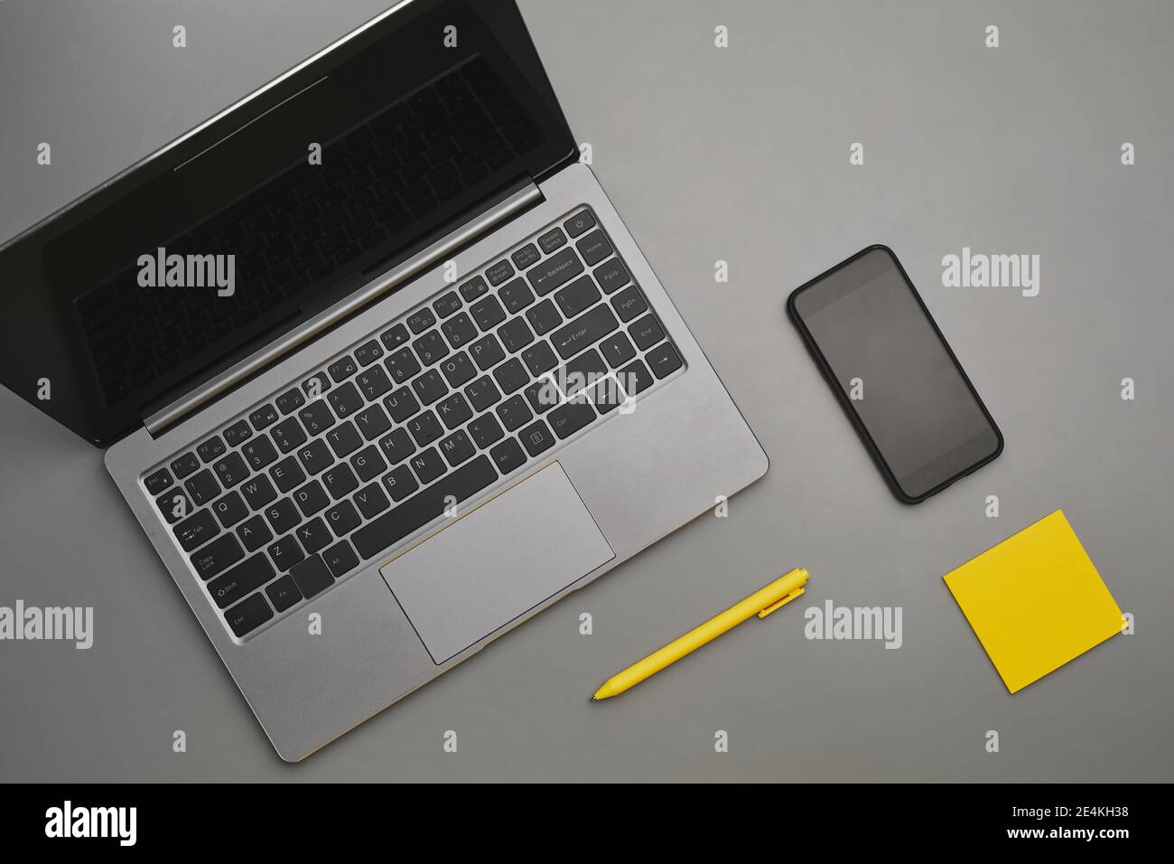 Sfondo grigio e giallo grafico di computer portatile e smartphone con accessori aziendali alla scrivania, vista dall'alto in piano, spazio per la copia Foto Stock