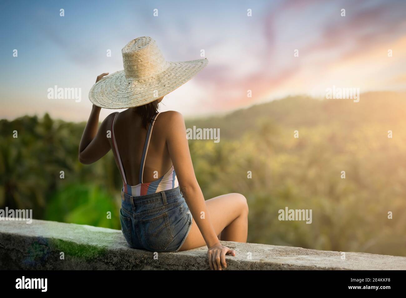 (Fuoco selettivo) vista mozzafiato di una ragazza con un grande cappello di paglia che guarda la foresta di palme è Siargao, Filippine. Foto Stock