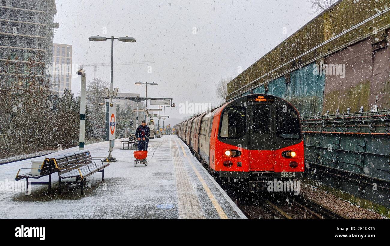 Il lavoratore della TFL applica in fretta il sale granato alla piattaforma ferroviaria della stazione della metropolitana di Colindale mentre nevica il 24 gennaio 2021. I trasporti per Londra non sono preparati per il maltempo sulla rete metropolitana di Londra depite Met Office avvertenze meteo sono in atto per la nevicata pesante. Colindale, Londra. Regno Unito Meteo. Foto Stock