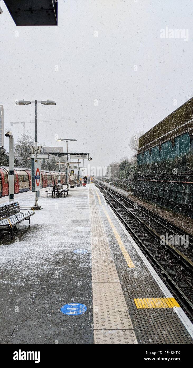 Il lavoratore della TFL applica in fretta il sale granato alla piattaforma ferroviaria della stazione della metropolitana di Colindale mentre nevica il 24 gennaio 2021. Il trasporto per Londra non è preparato per il maltempo sulla rete metropolitana di Londra nonostante gli avvertimenti meteorologici del MET Office siano in atto per le forti nevicate. Colindale, Londra. Regno Unito Meteo. Foto Stock