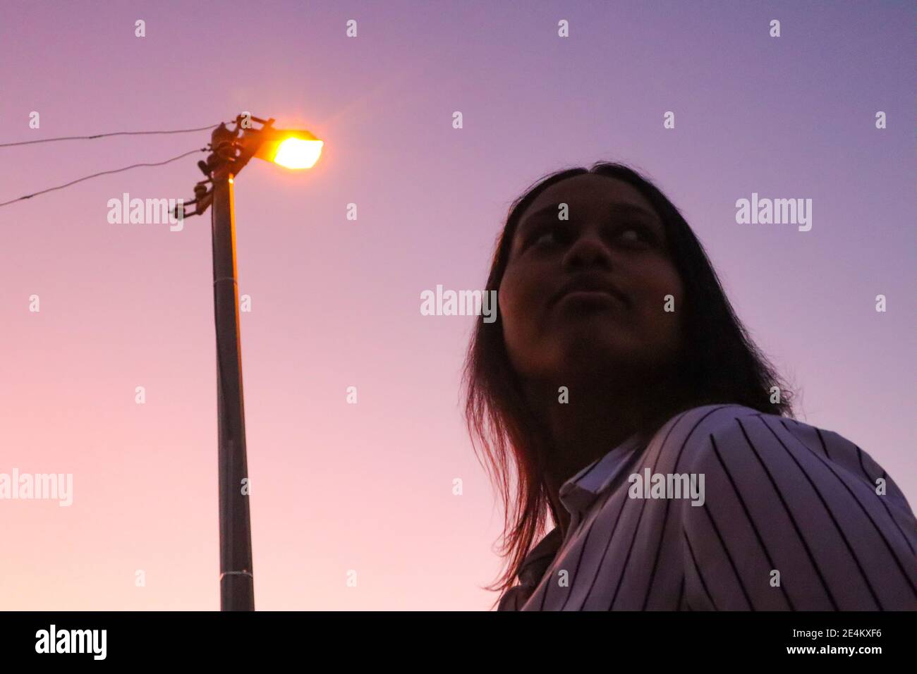 Città del Capo, Sud Africa - 20-02-2020 Creatore e violaceo tramonto e lampada da strada. Elegante giovane donna in primo piano. Foto Stock