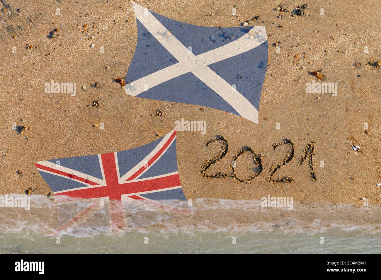 2021 in Sand geschrieben , Schottische Flagge, die Bridische Flagge wird von wasser überspült Foto Stock