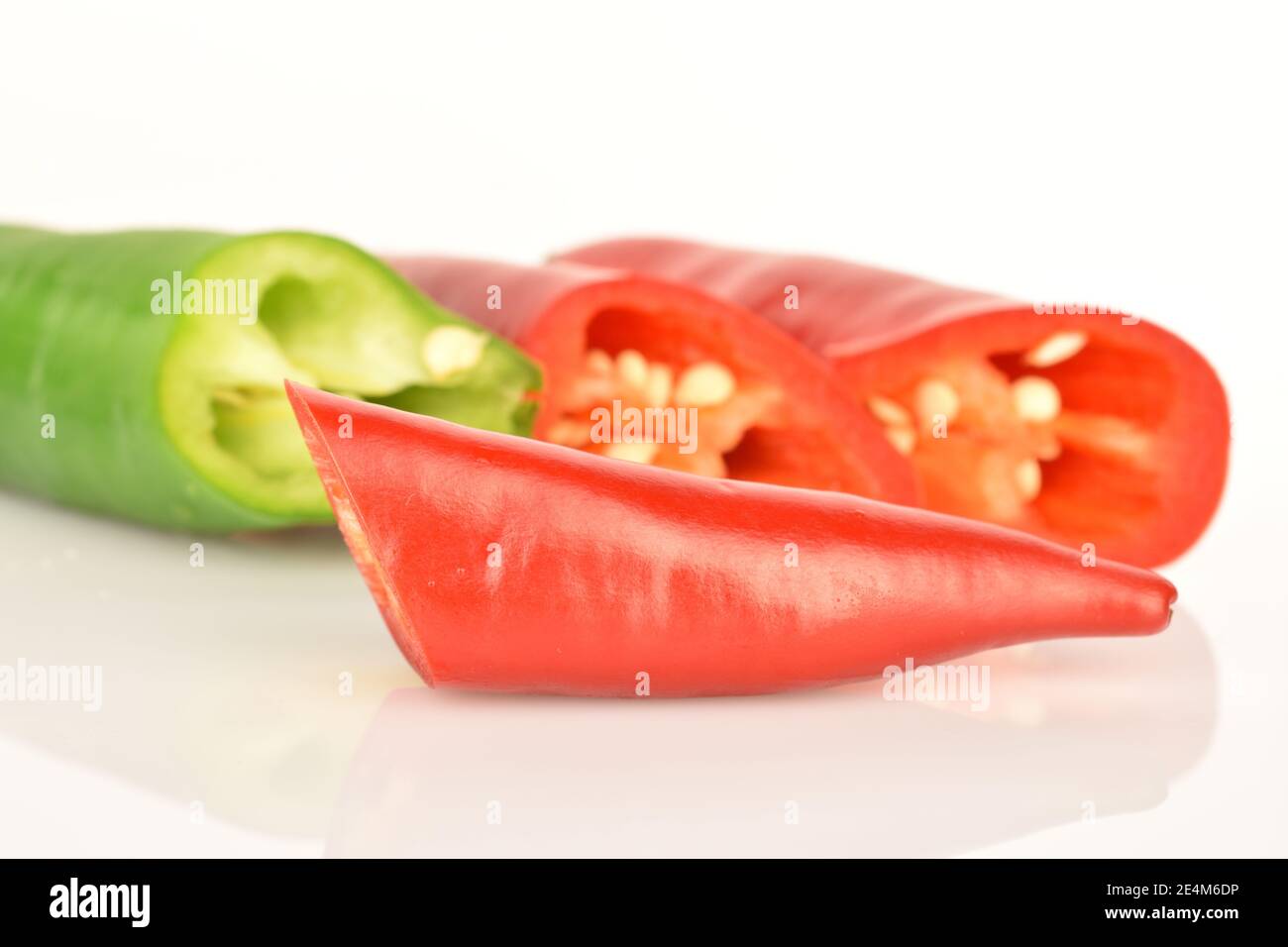Tre peperoni caldi, rossi e verdi, freschi e speziati, su sfondo bianco. In primo piano in primo piano, macro, a fette di pepe rosso. Foto Stock