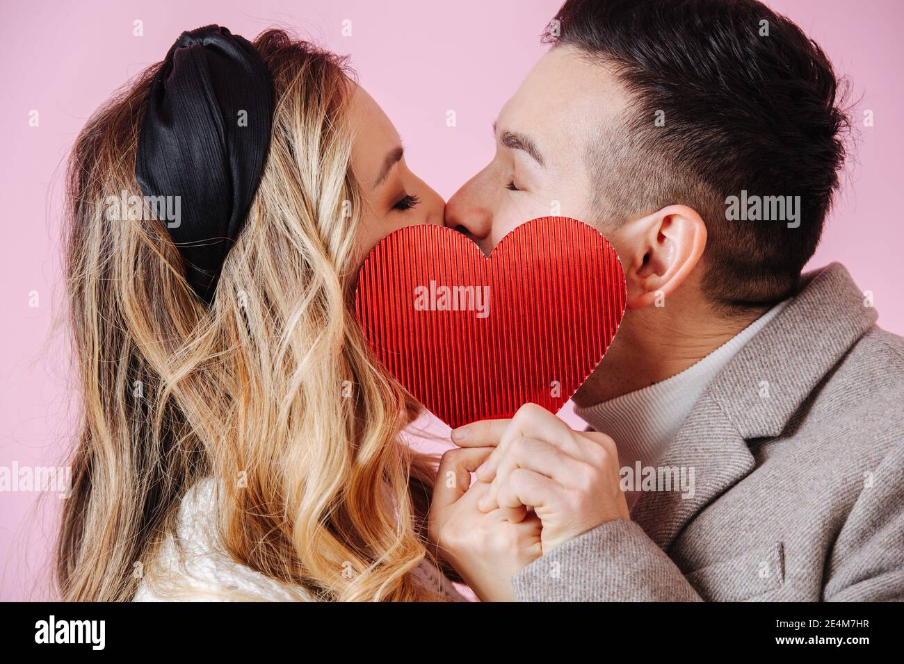 San Valentino. Primo piano bacio nascosto dal cuore rosso Foto Stock
