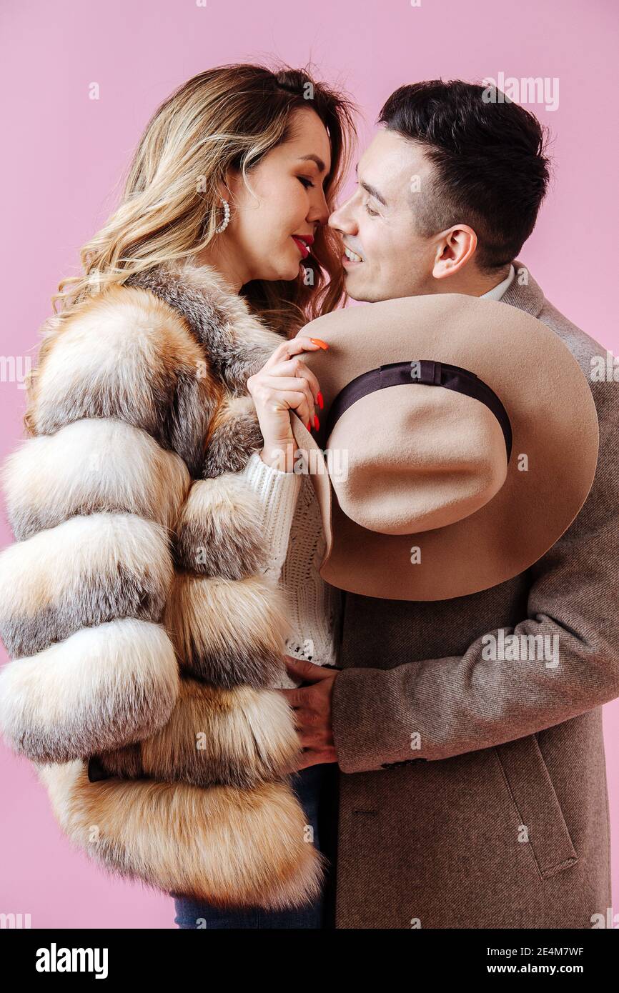 La coppia in coccole d'amore, sono in abiti invernali con un cappello nelle loro mani Foto Stock