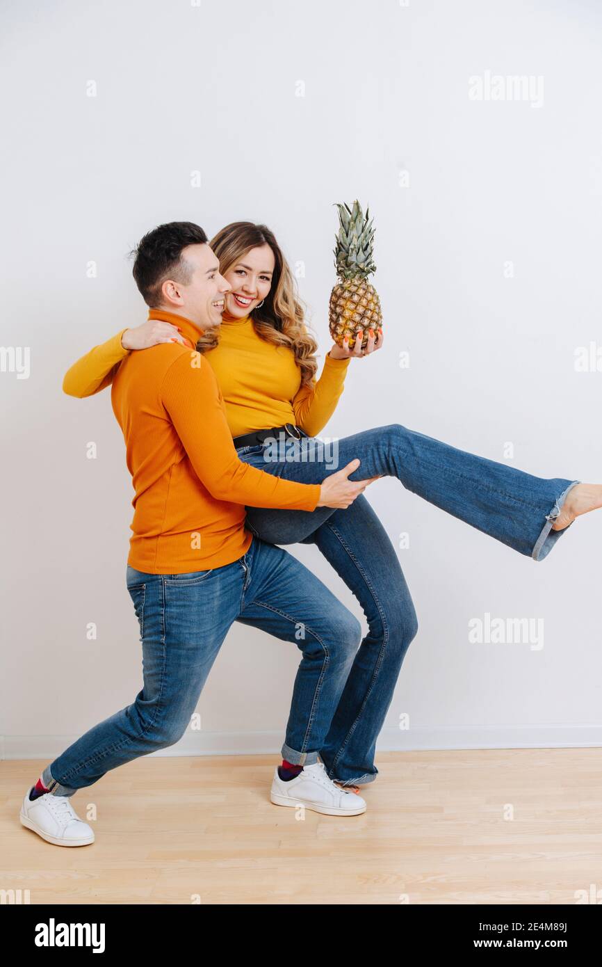 Una coppia divertente si scioglieva intorno e danzare tenendo un ananas dentro la sua mano Foto Stock