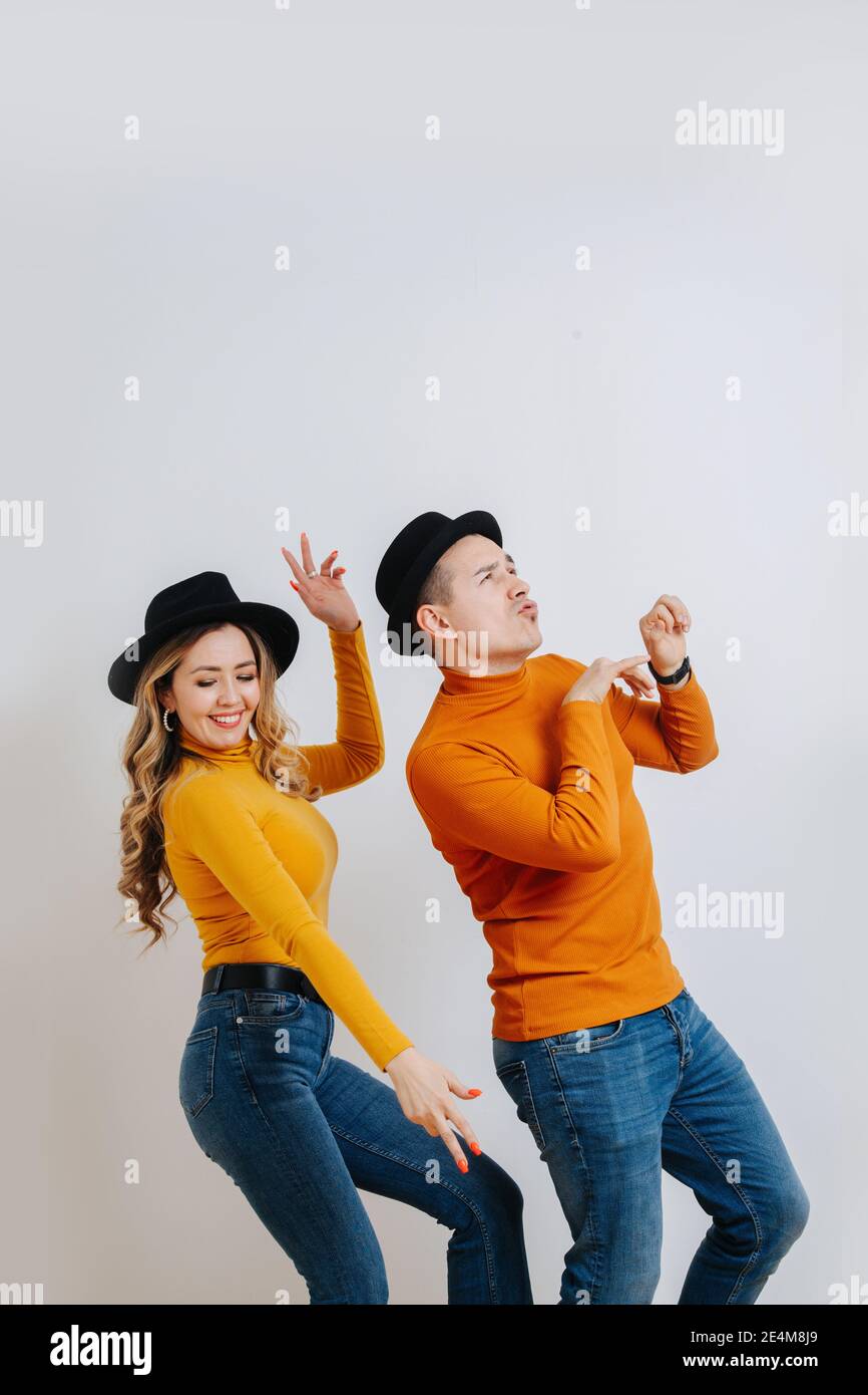 Una coppia esilarante si diverte a ballare contro la parete grigia Foto Stock