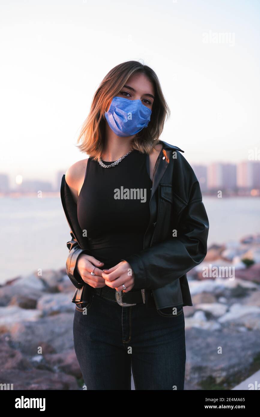 Ritratto di una ragazza adolescente con una maschera medica sulla strada. Foto Stock