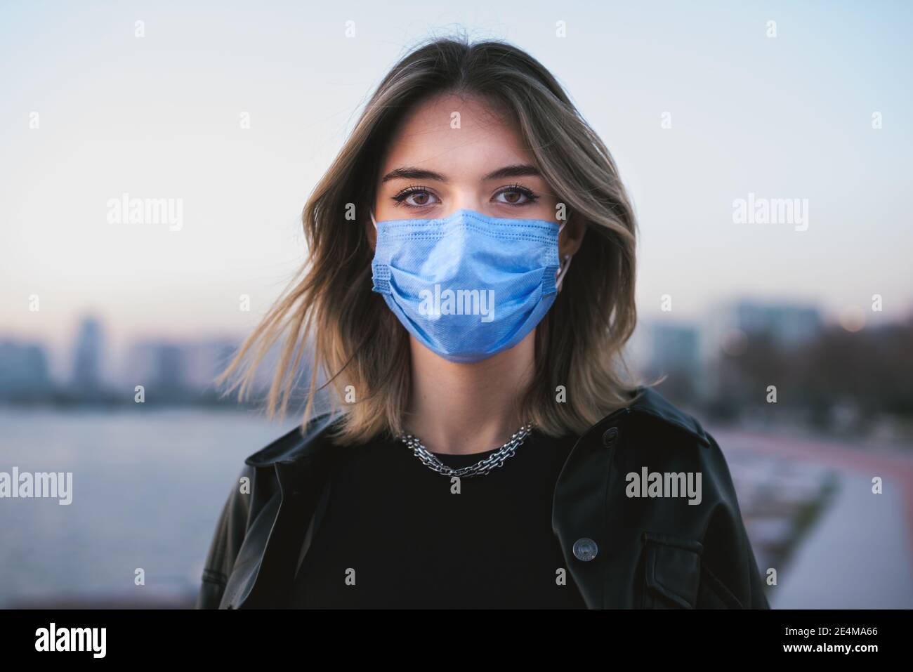 Ritratto di una ragazza adolescente con una maschera medica sulla strada. Foto Stock