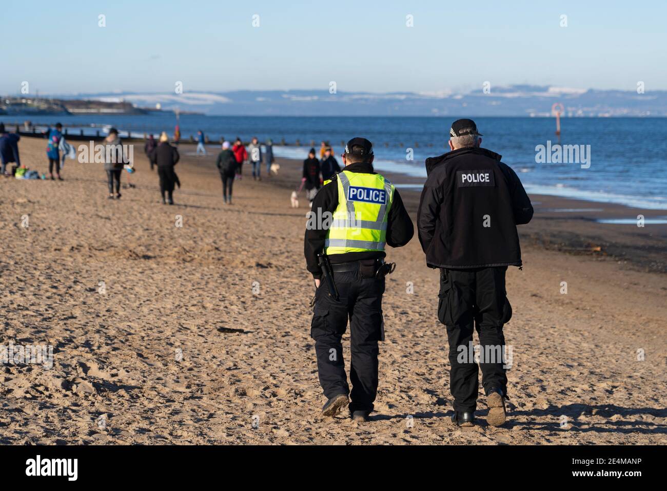 Portobello, Scozia, Regno Unito. 24 gennaio 2021. Gran numero di membri del pubblico alla spiaggia di Portobello e lungomare sulla soleggiata Domenica pomeriggio durante la chiusura. Mentre la maggior parte della gente ha osservato i gruppi sociali di distanza della gente si sono formati ad alcuni dei caffè che offrono il cibo e le bevande del take-away. I pattugliatori della polizia hanno parlato con il pubblico seduto e in gruppi nei caffè per chiedere loro di andare avanti. Iain Masterton/Alamy Live News Foto Stock