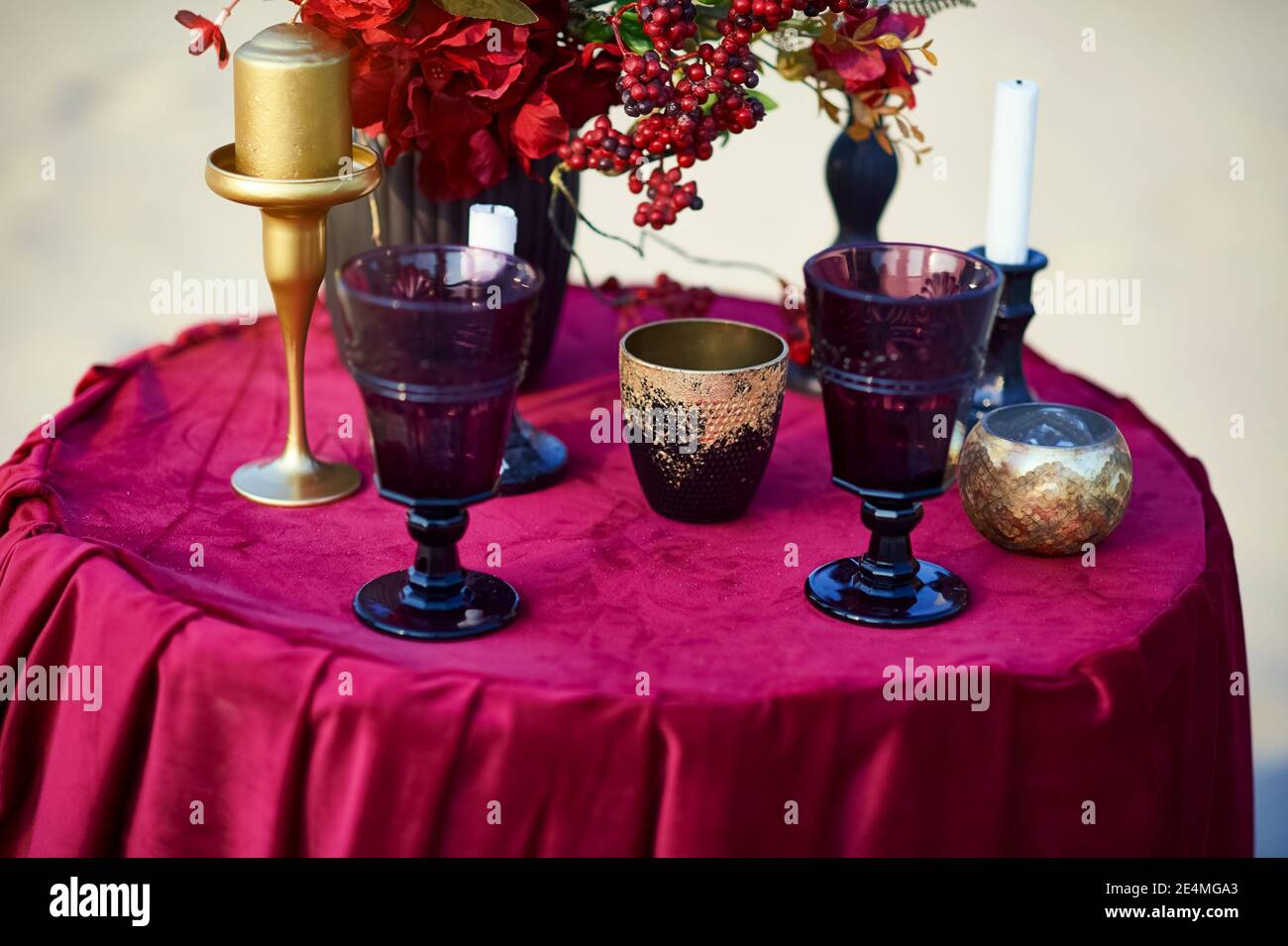 Bicchieri da vino e candelabri sul tavolo rosso. Foto Stock