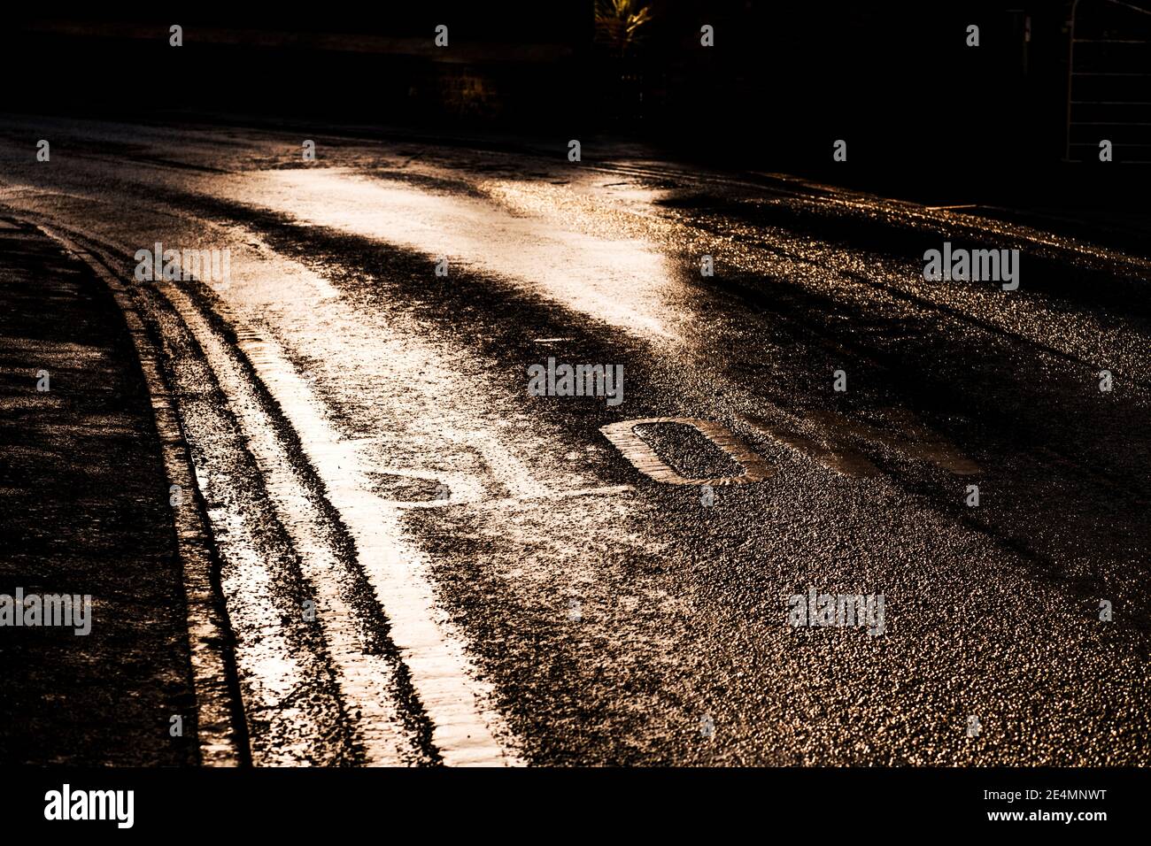 Segno lento dipinto su una strada in Bugbrooke, Northamptonshire in bassa luce solare d'inverno Foto Stock