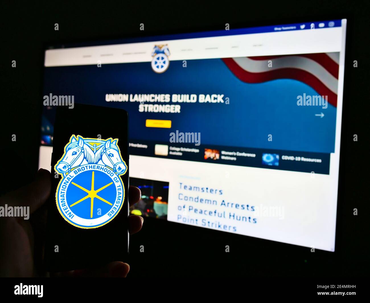 Persona che tiene uno smartphone con il logo del sindacato International Brotherhood of Teamsters sullo schermo. Concentrarsi sul centro dello schermo del telefono cellulare. Foto Stock