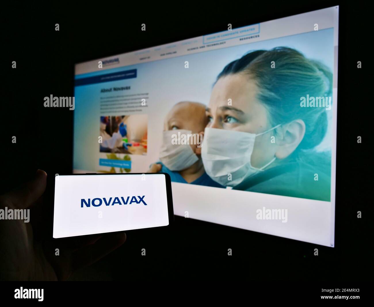Persona che detiene il telefono cellulare con il logo della società di sviluppo vaccino US Novavax Inc. Sullo schermo di fronte al sito web aziendale. Mettere a fuoco il display del telefono. Foto Stock