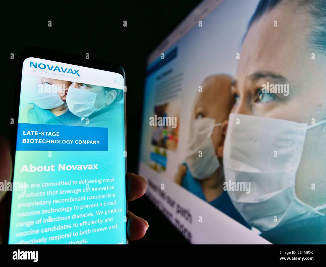 Persona che detiene cellulare con il logo della società di sviluppo vaccino US Novavax Inc. Sullo schermo davanti alla pagina web. Focus sul display del telefono cellulare. Foto Stock