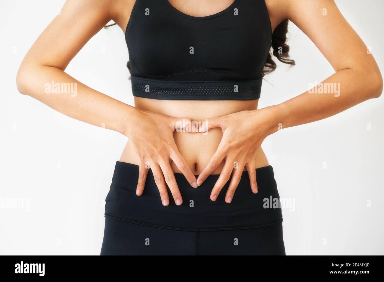 Immagine ravvicinata di giovane donna in sportswear messa a forma di cuore gesto a suo addome. Dieta perdita di peso e di nutrizione sana nozione. Foto Stock