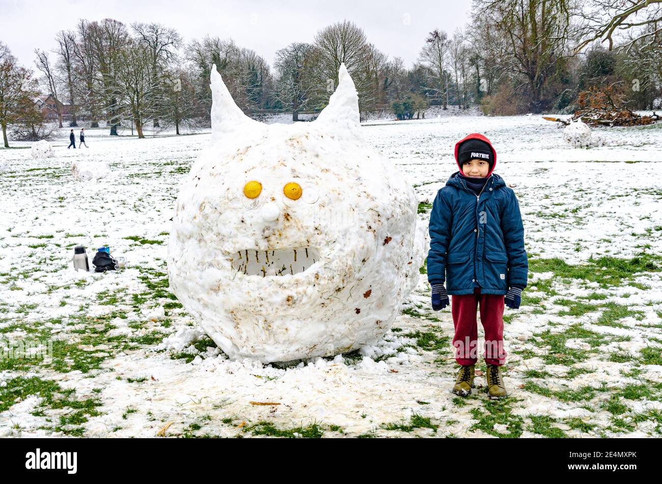 Un ragazzo si trova accanto a una creatura simile a un bruco scolpito dalla neve nel Prospect Park, Reading, Regno Unito, nel bel mezzo dell'inverno. Foto Stock
