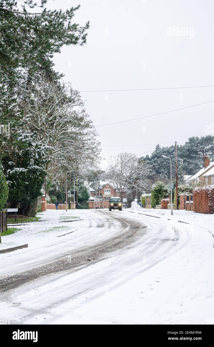 I cingoli degli pneumatici conducono intorno ad una curva su una strada innevata a Reading, Berkshire, Regno Unito Foto Stock