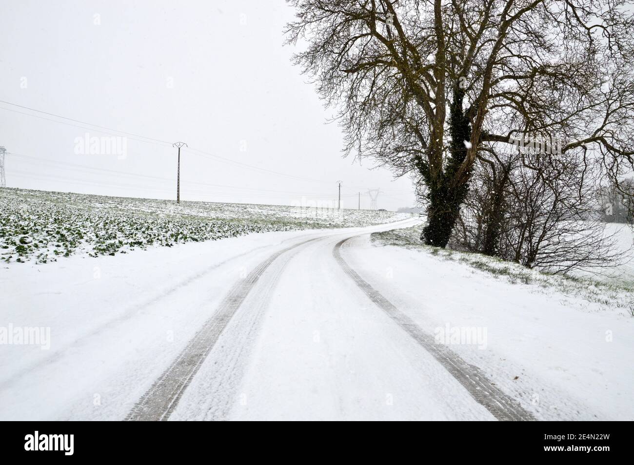 Una strada di campagna nevosa, pericolosa e scivolosa durante la nevicata invernale. Foto Stock
