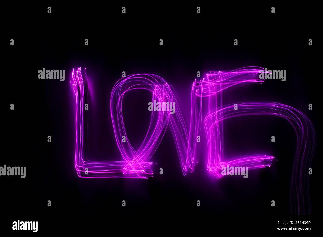 Parola 'amore' scritta in luce rosa su sfondo nero. Foto con luce al neon a lunga esposizione. Febbraio 14 concetto di San Valentino. Sfondo al neon. Foto Stock