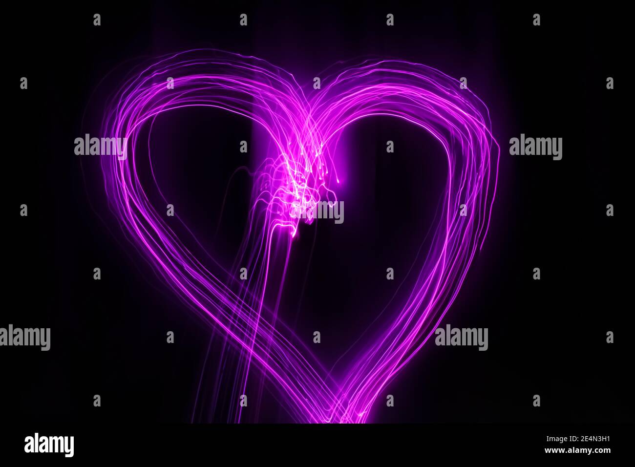 Forma del cuore disegnata con luci rosa su sfondo nero. Fotografia a lunga esposizione. Febbraio 14 concetto di San Valentino. Foto Stock