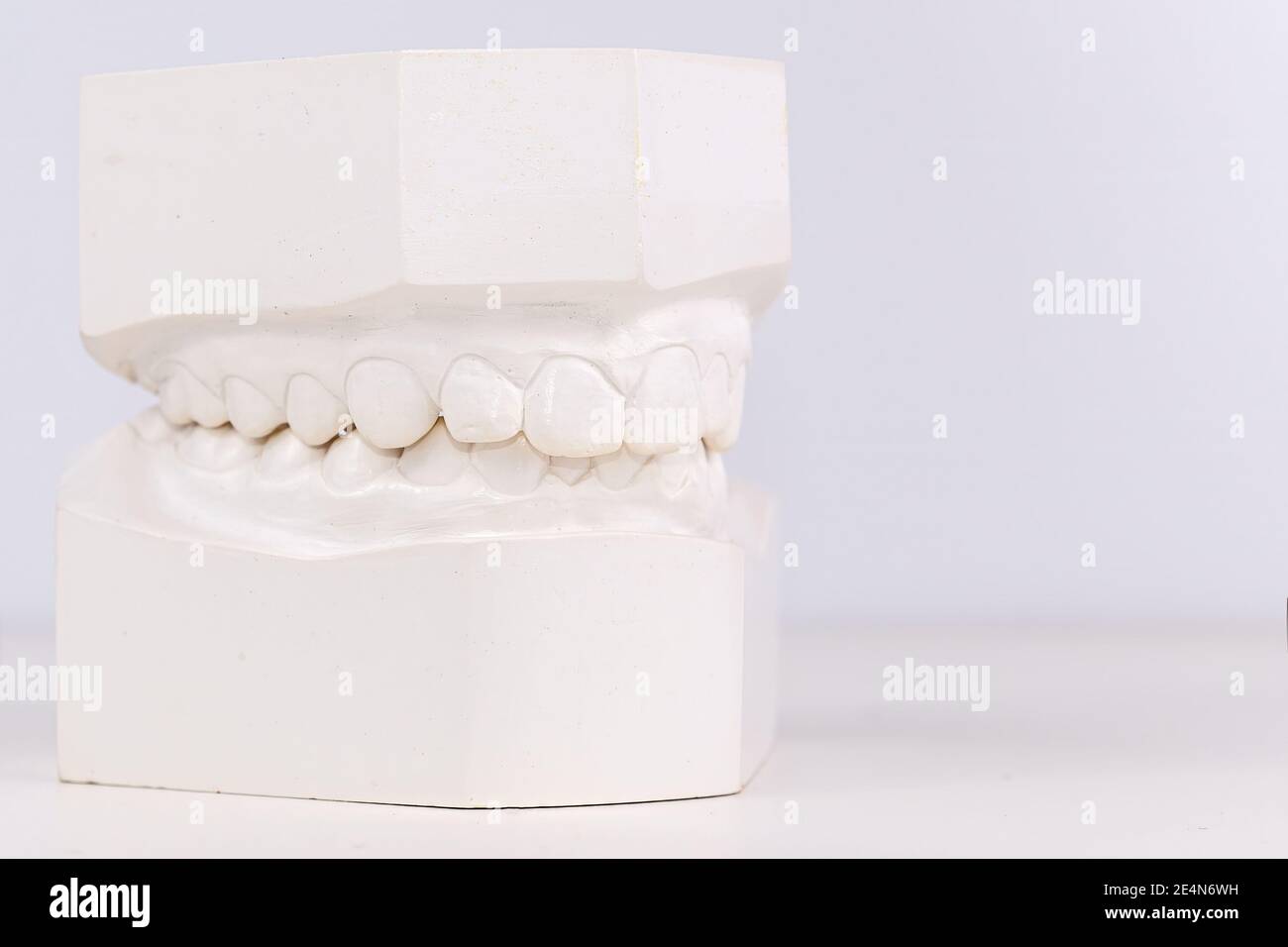 Denti umani dentali bianchi che colano su sfondo bianco. Vista in primo piano ad angolo basso. Ganasce superiore e inferiore. Profondità di campo poco profonda. Foto Stock