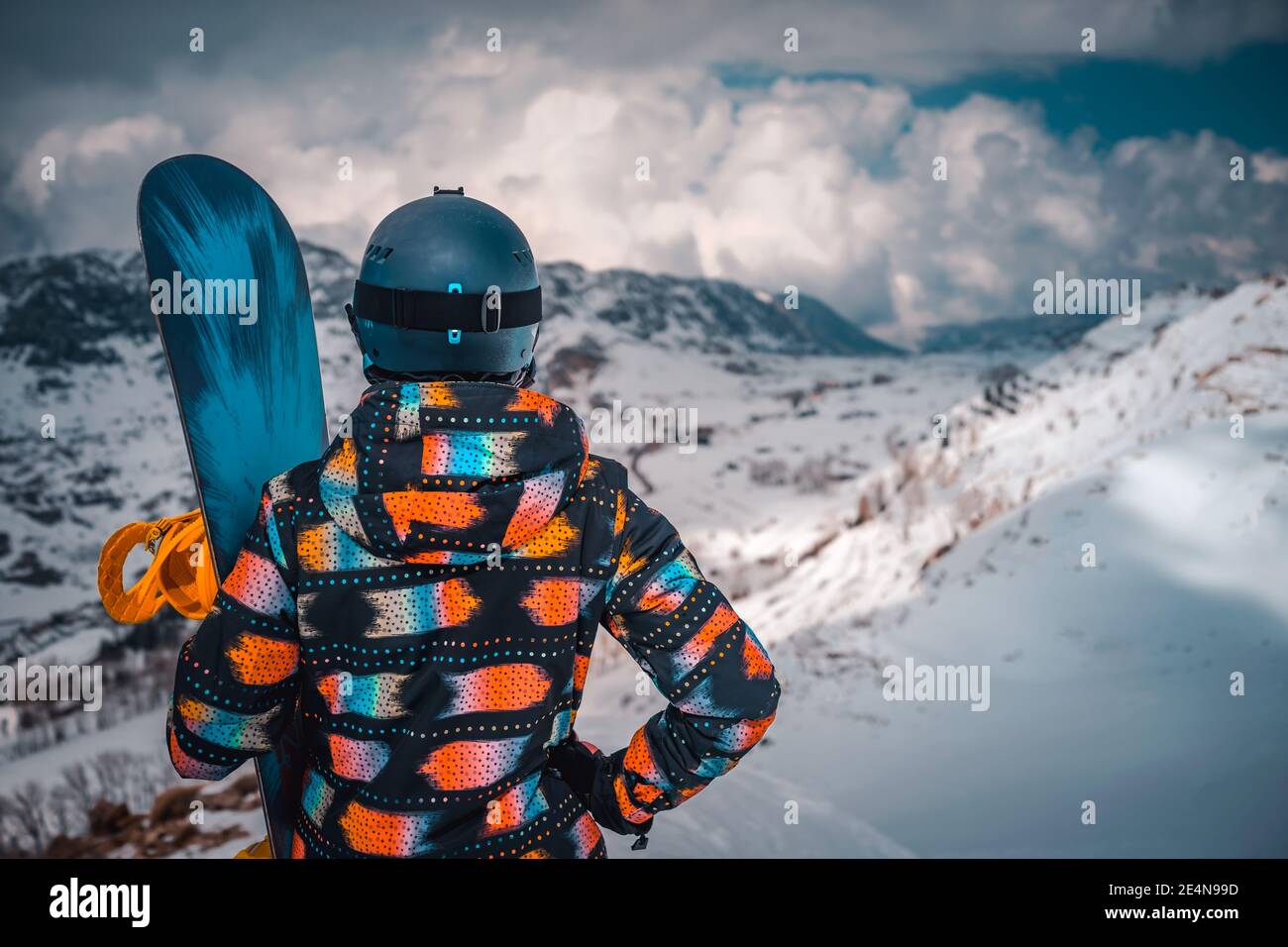Vista posteriore di un snowboarder femminile godendo di una vista incredibile di una montagna Snowy. Stile di vita sano attivo. Trascorrere le vacanze invernali nella stazione sciistica. Foto Stock