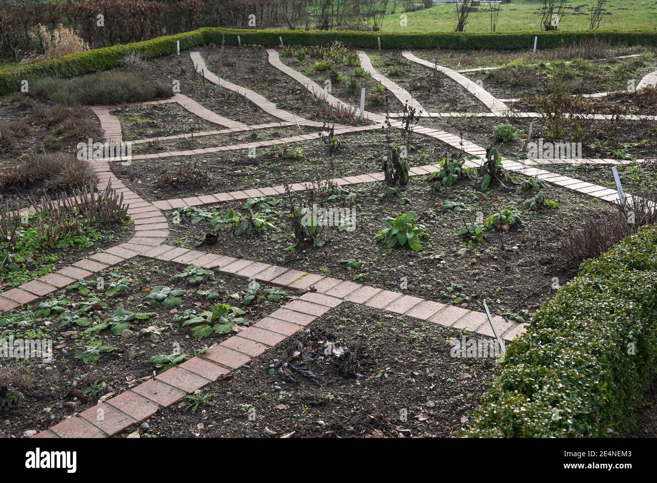 Orto e orto con letti raccolti, taglio piante perenni e sentieri in mattoni tra l'attesa di primavera, fuoco selezionato, profondità stretta di Foto Stock