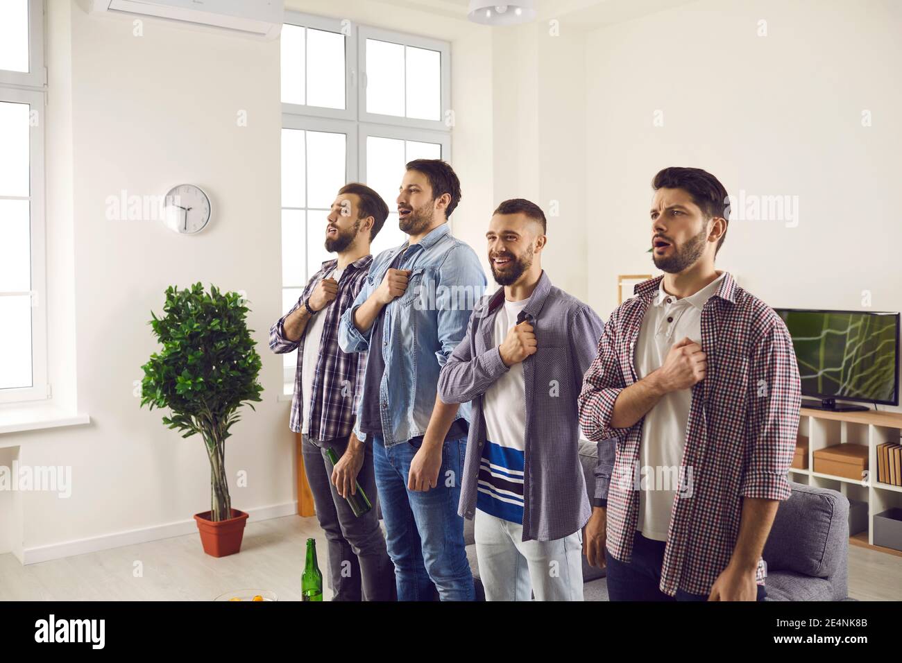 Felici e orgogliosi tifosi di calcio che tengono le mani al petto e cantano inno nazionale Foto Stock